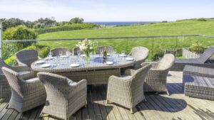 Villa 27 balcony. Dining table and chairs. Sun lounges. View of the Tennis court lawn and ocean.