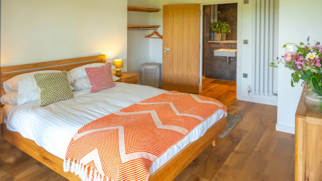 Villa bedroom. Double bed with bedside table. Doorway to the ensuite at the back of the image. Cabinet opposite the end of the bed.