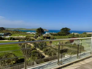 View off a balcony onto the hotel gardens and seaside area. The sea and headland in the distance.